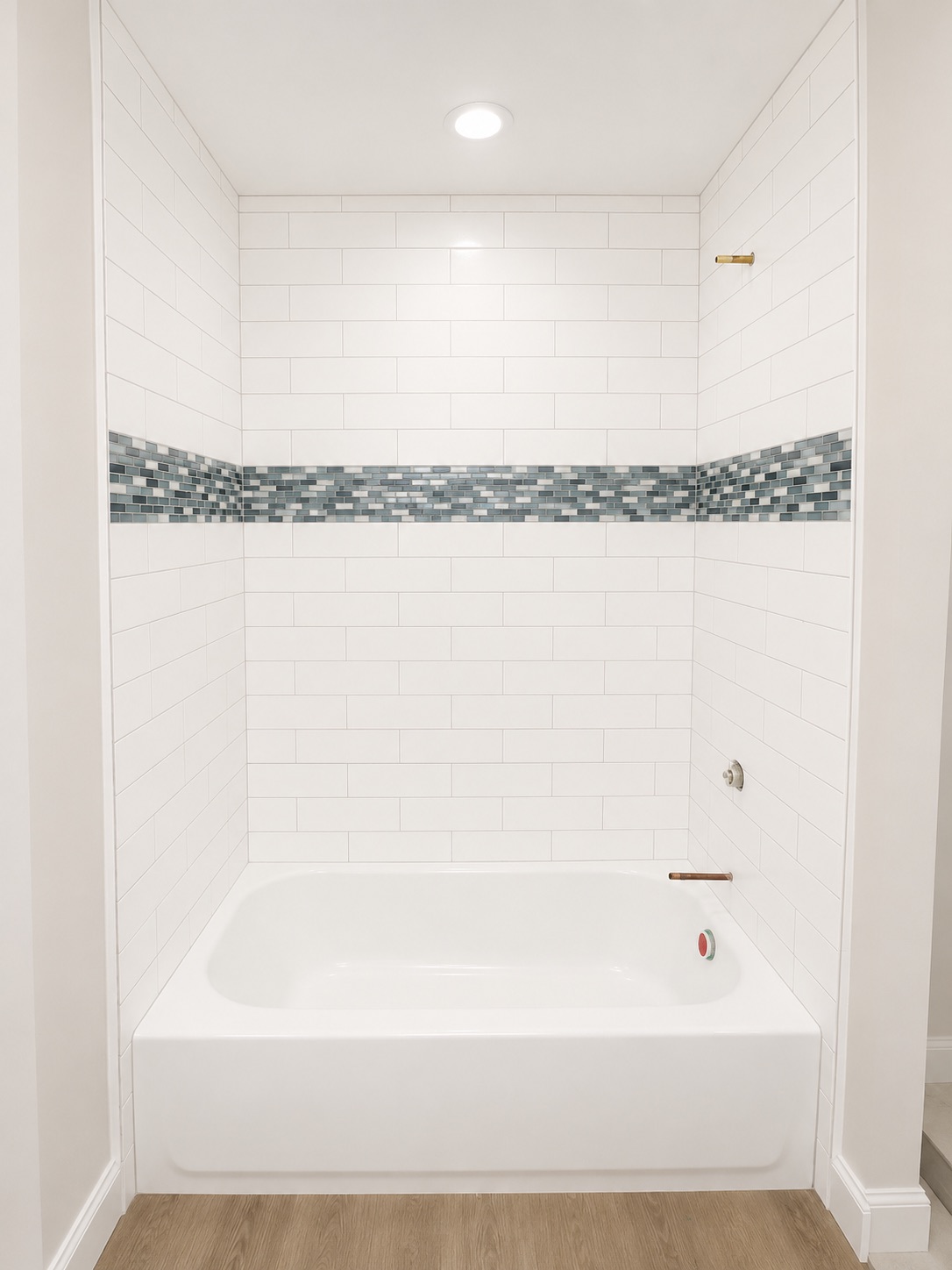 Tub with white subway tile and blue mosaic border