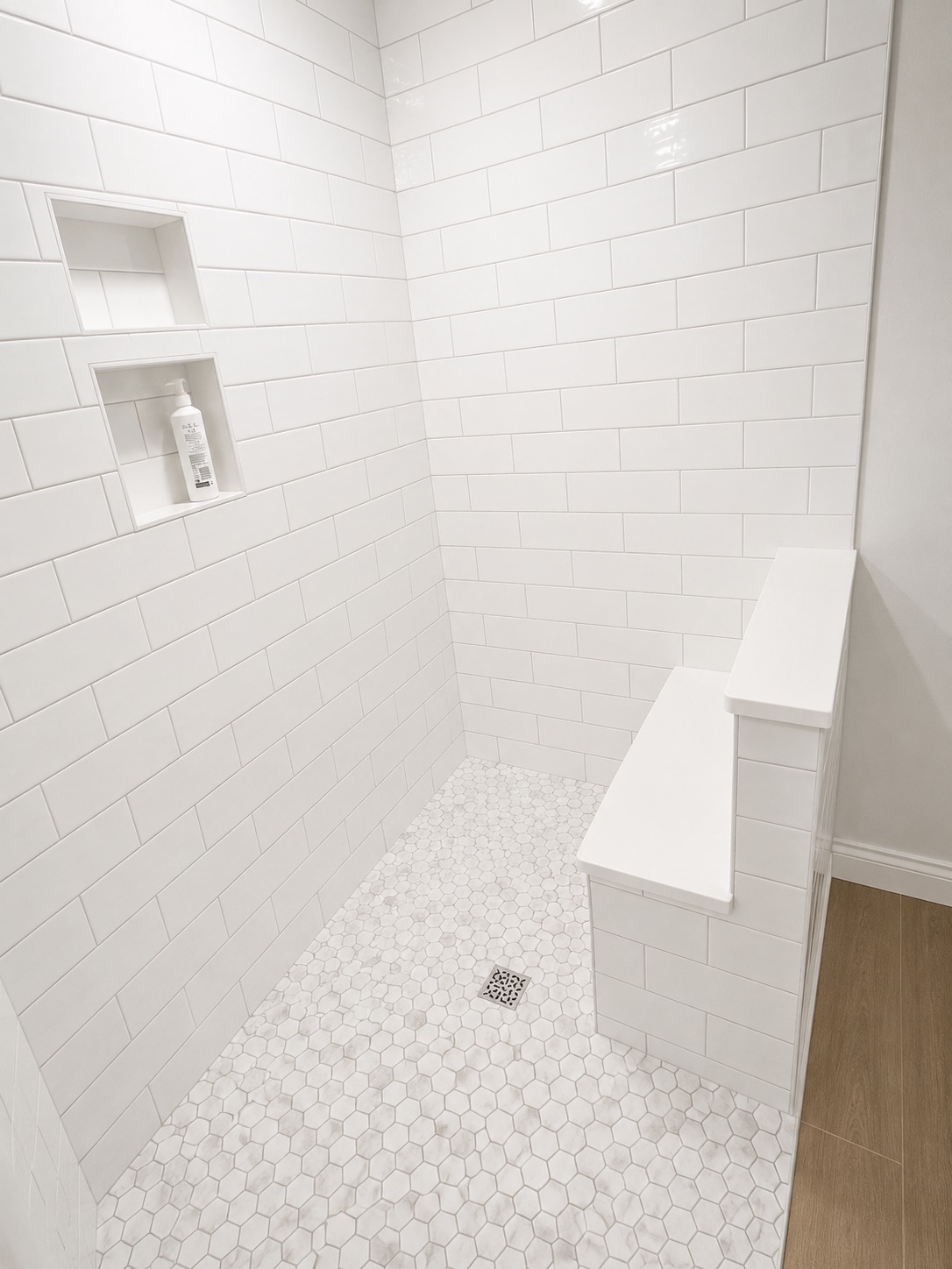 Shower with white subway tile, built-in bench and hexagonal floor