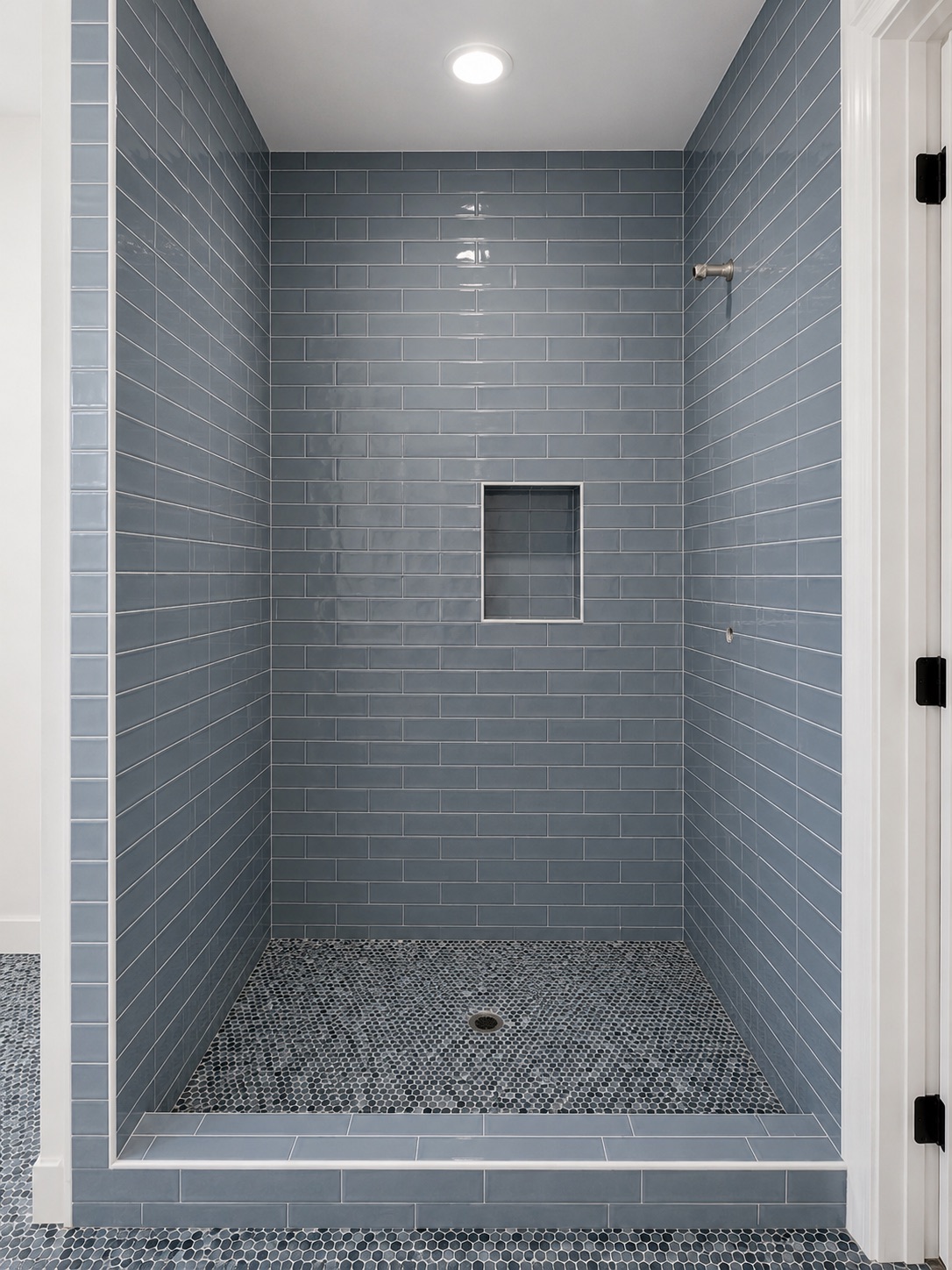 Shower with blue subway tile and penny mosaic floor