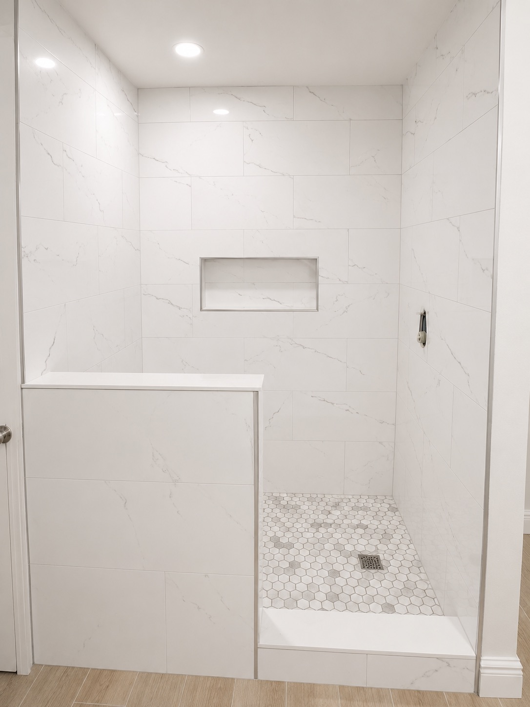 White marble shower with recessed niche and hexagonal floor