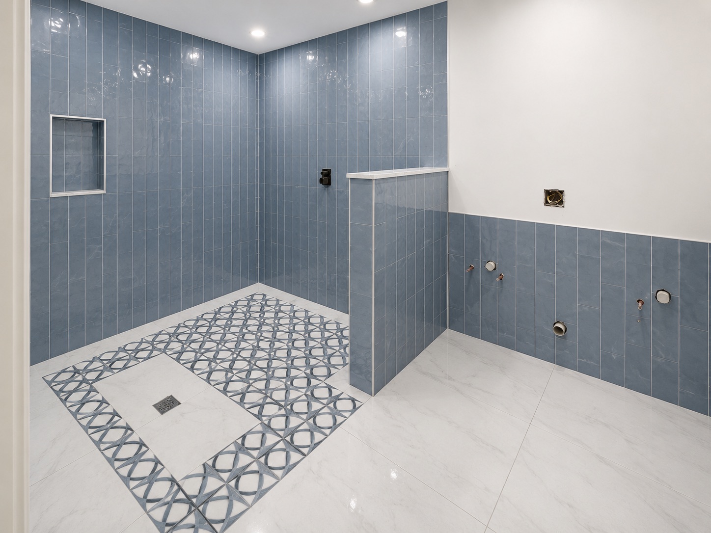 Shower with vertical blue tile and geometric mosaic floor