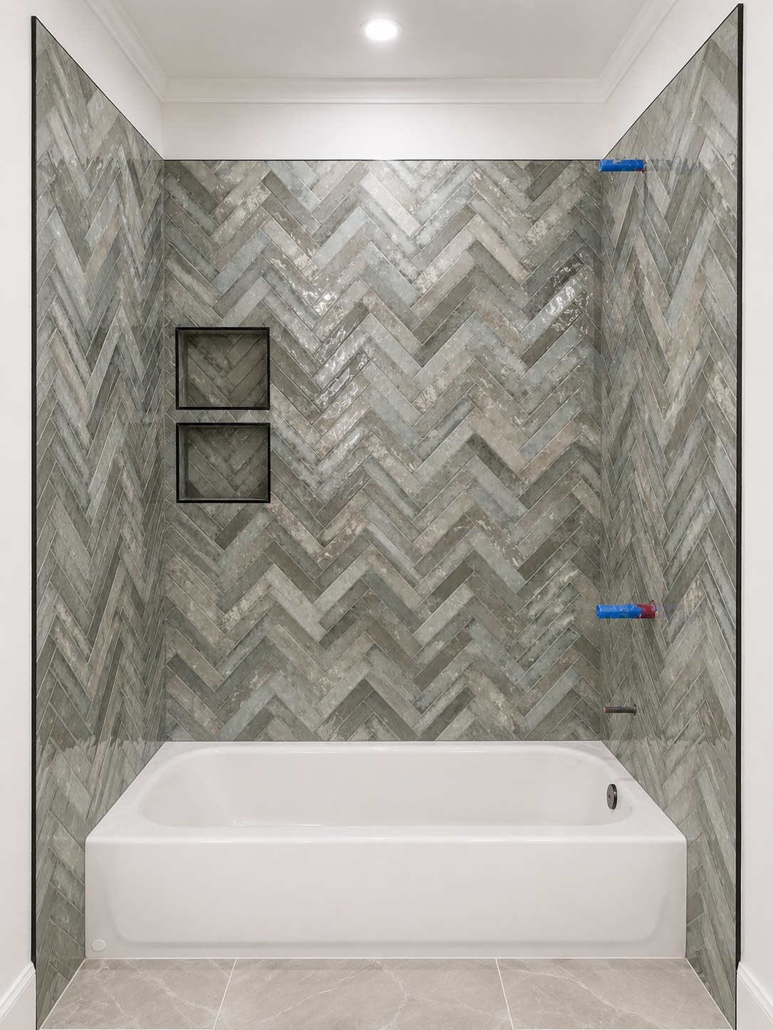 Tub with gray herringbone tile and black niches